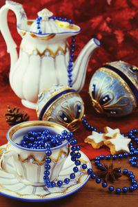 Close-up of christmas baubles by antique crockery with bead jewelry on table