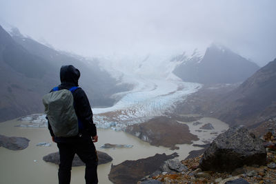 Rear view of man standing on snowcapped mountain