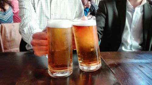 Midsection of man with beer standing on table