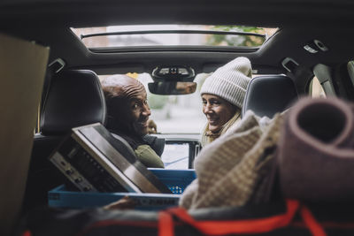 Happy mature couple looking back at luggage in car