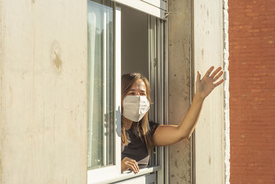 Woman gesturing while leaning from window