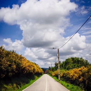 Empty road against cloudy sky