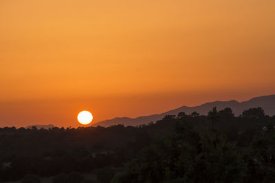 Scenic view of silhouette mountains against orange sky