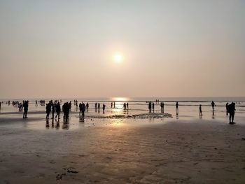 Silhouette people on beach against sky during sunset