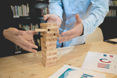 Cropped hands playing with wooden blocks on table