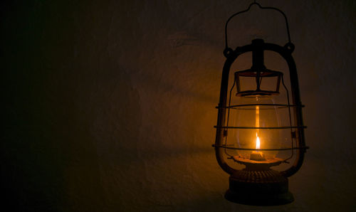 Close-up of illuminated light bulb hanging against wall