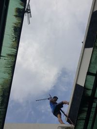 Low angle view of man holding umbrella against sky
