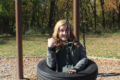 Young woman sitting on swing in park