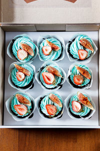 The plate of tasty cupcakes decorated with strawberry, fig and cream