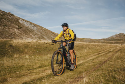 Female riding electric bicycle on mountain at somiedo natural park, spain