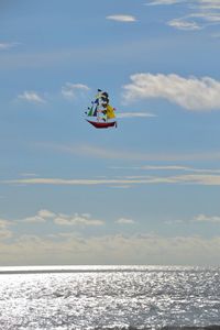 Boat shaped kite flying over sea against sky