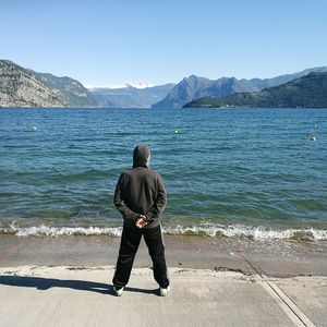 Rear view of man standing on beach against clear sky