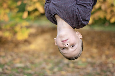 Portrait of cute boy hanging upside down in park