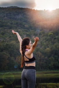 Woman standing against mountain during sunset