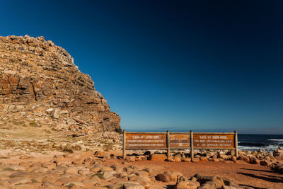 Rock formation on beach against clear blue sky