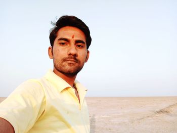 Portrait of young man standing on land against clear sky