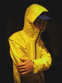 Man wearing yellow hood in darkroom