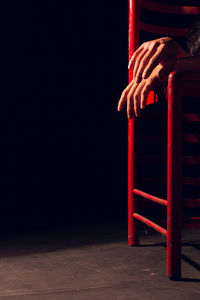 Low section of person on red chair against wall