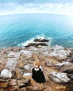 Rear view of woman standing by sea against sky