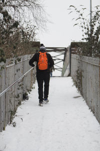 Rear view of man walking on footpath during winter