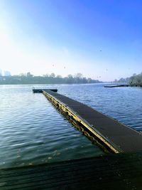 Pier over lake against clear blue sky