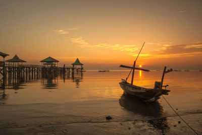 Boat moored on sea against sky during sunset