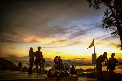 People at beach against sky during sunset