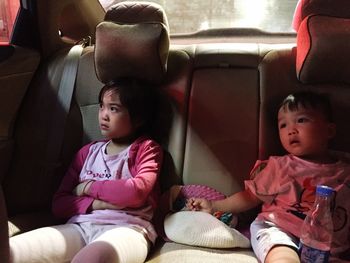 Sad siblings sitting in car