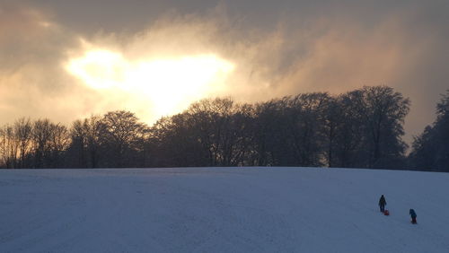 Snow covered field against sky during winter