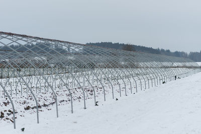 Fence on snow covered field against sky