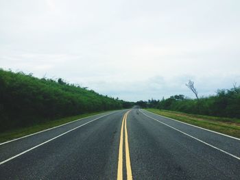 Road amidst trees against sky