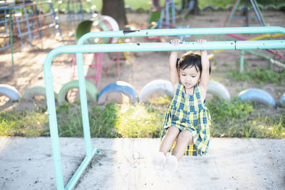 Portrait of young woman sitting on slide at playground