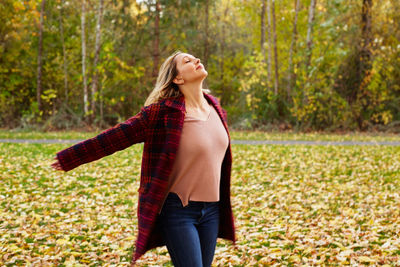 Young woman standing against autumn trees at park