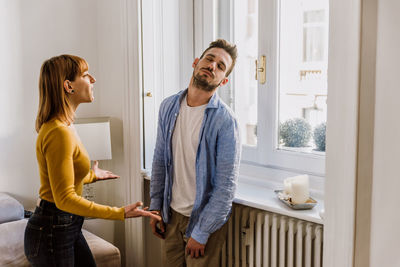 Young couple standing against window at home