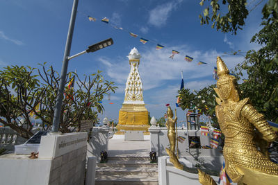 Statue by building against sky