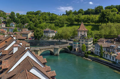 Bridge over river by buildings against sky