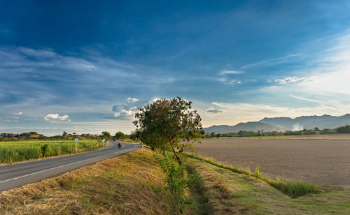 Road amidst field against sky