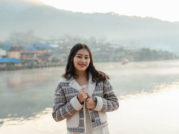 Portrait of young woman standing against sky