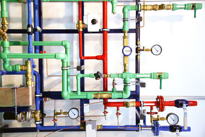 Colorful metallic pipes with gauge against wall