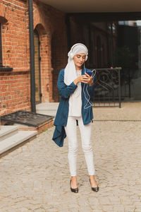 Full length of young woman using mobile phone