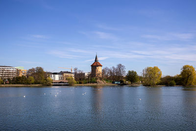 Buildings by river against sky