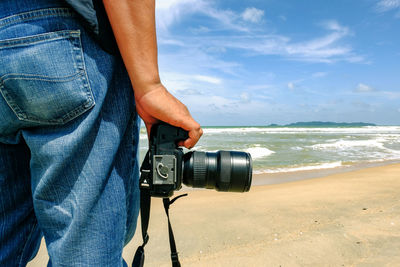 Man holding camera on beach