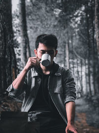 Portrait of young man standing in forest, coffe lover