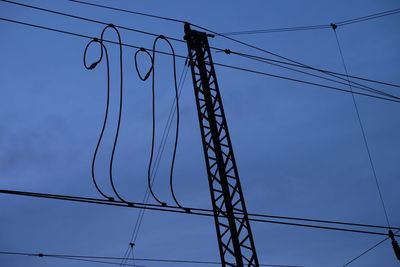 Low angle view of electricity pylon against blue sky