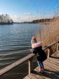 Side view of girl fishing in lake while standing by railing