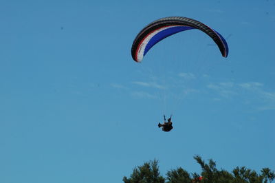 Low angle view of man paragliding against clear sky