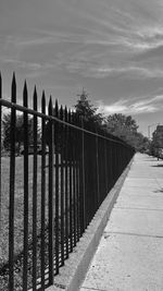 Footpath by fence against sky