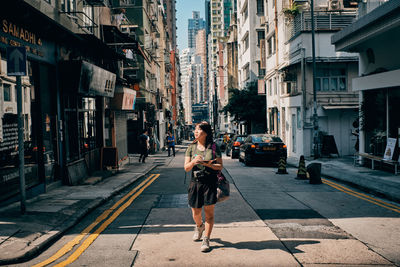 Woman on street amidst buildings in city