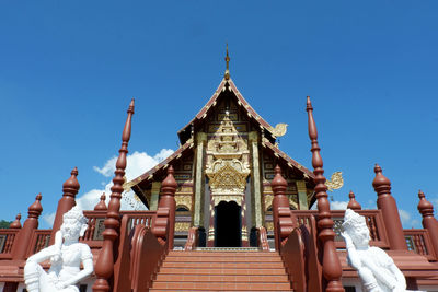 Low angle view of temple against building against clear blue sky