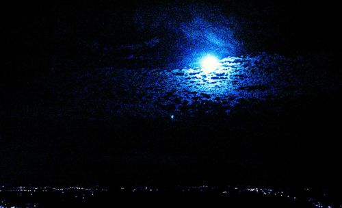 Low angle view of illuminated landscape against sky at night